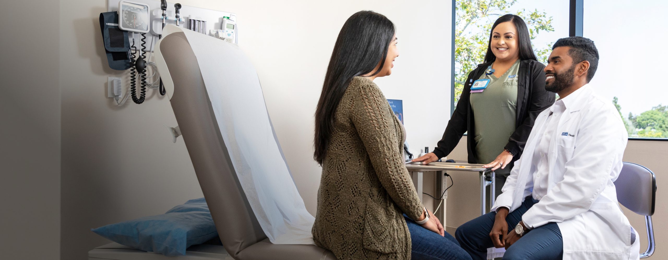 uclahea-cws-home-default Two UCLA Health clinical professionals consulting with a female patient at the bedside of a hospital room